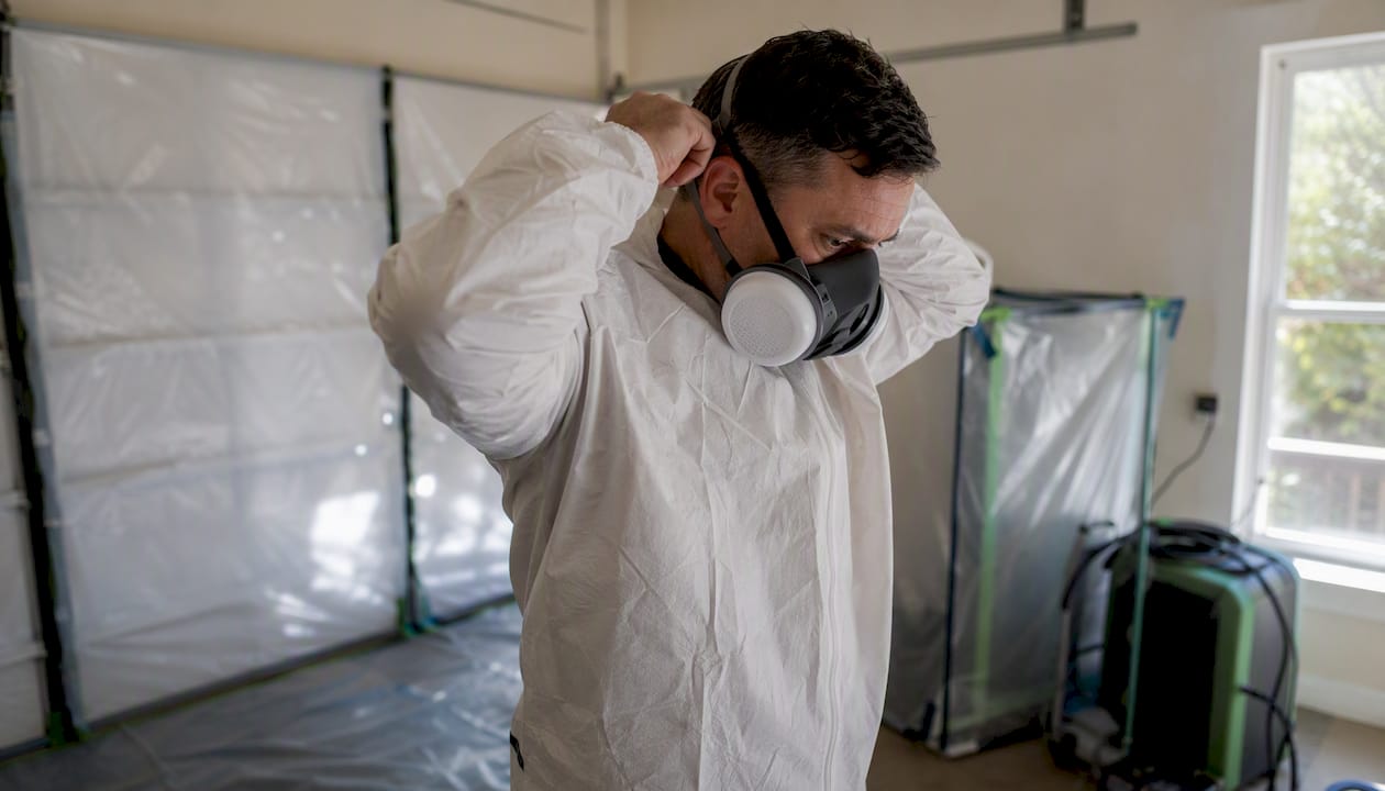 Worker putting on asbestos protective suit and respirator