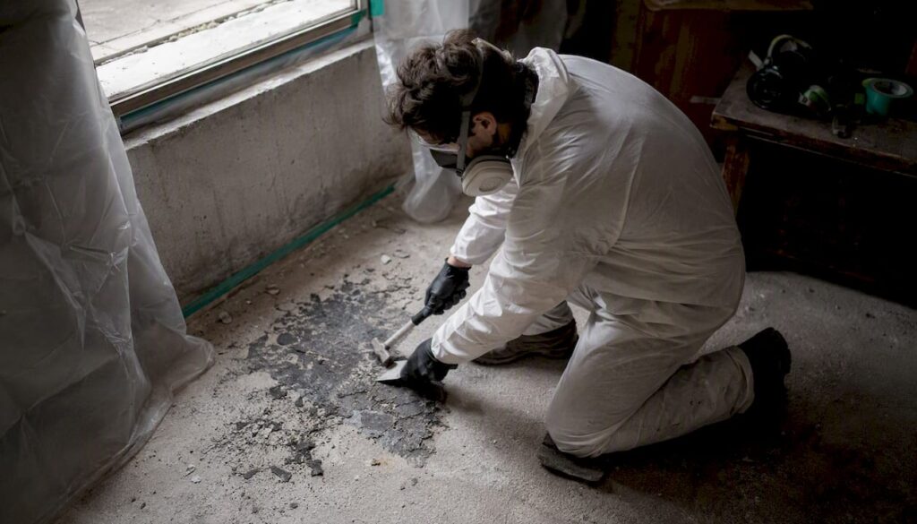 Technician scraping asbestos mastic from floor
