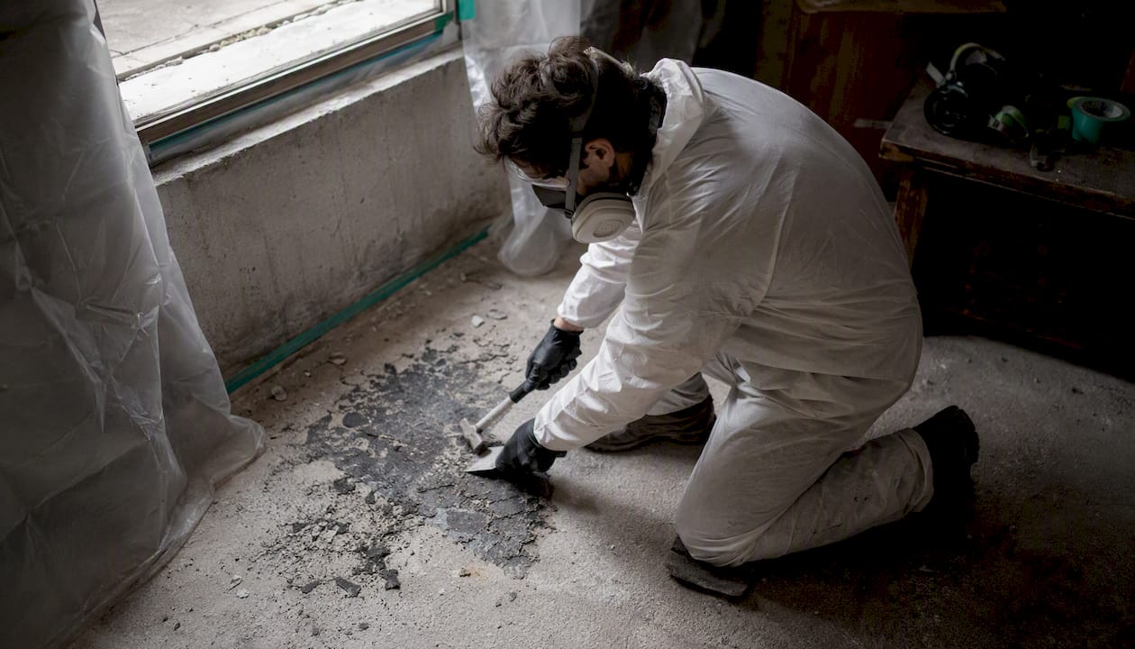 Technician scraping asbestos mastic from floor
