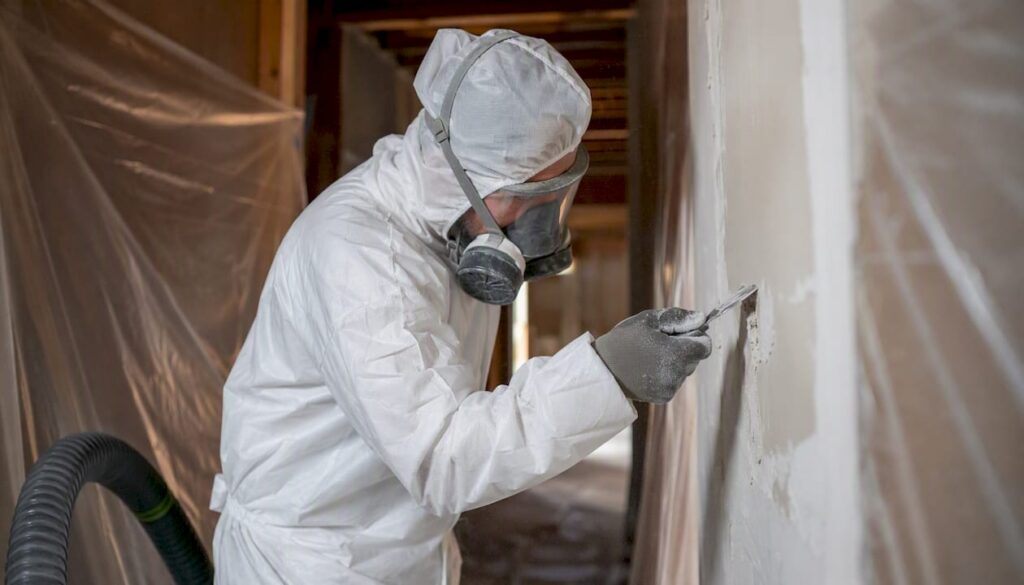Technician removing asbestos drywall mud safely