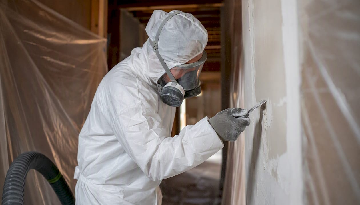 Technician removing asbestos drywall mud safely