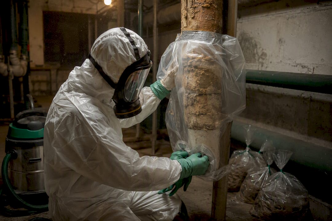 Technician installing glove bag on asbestos pipe