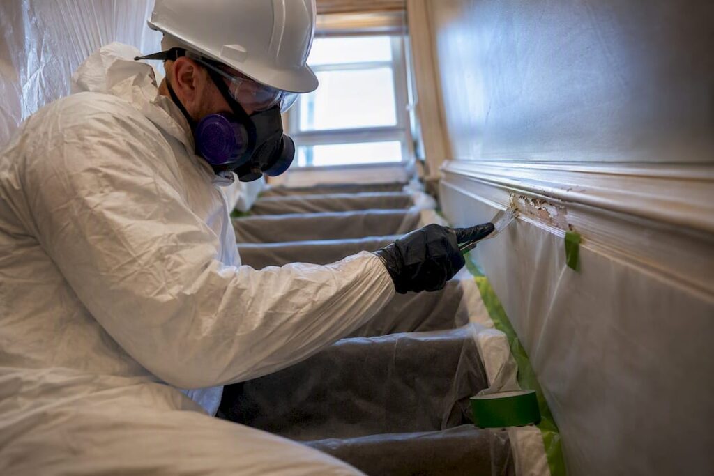 Technician removing layered paint in stairwell