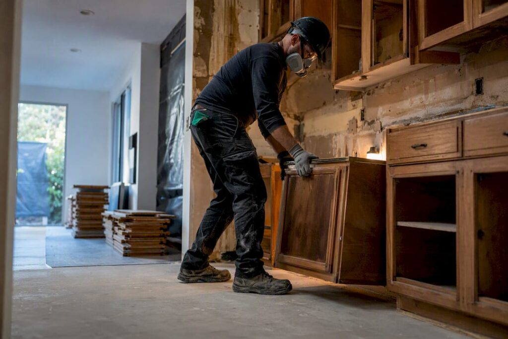 Worker removing cabinetry during soft strip demolition