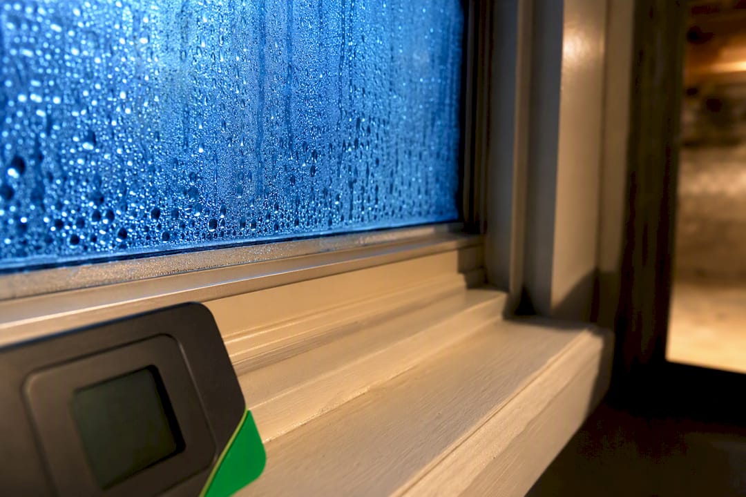 Condensation on basement window beside hygrometer